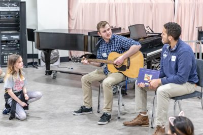 Alumnus Rex Sturdevant '17 (ED), MA '18 plays guitar for a group of elementary students.
