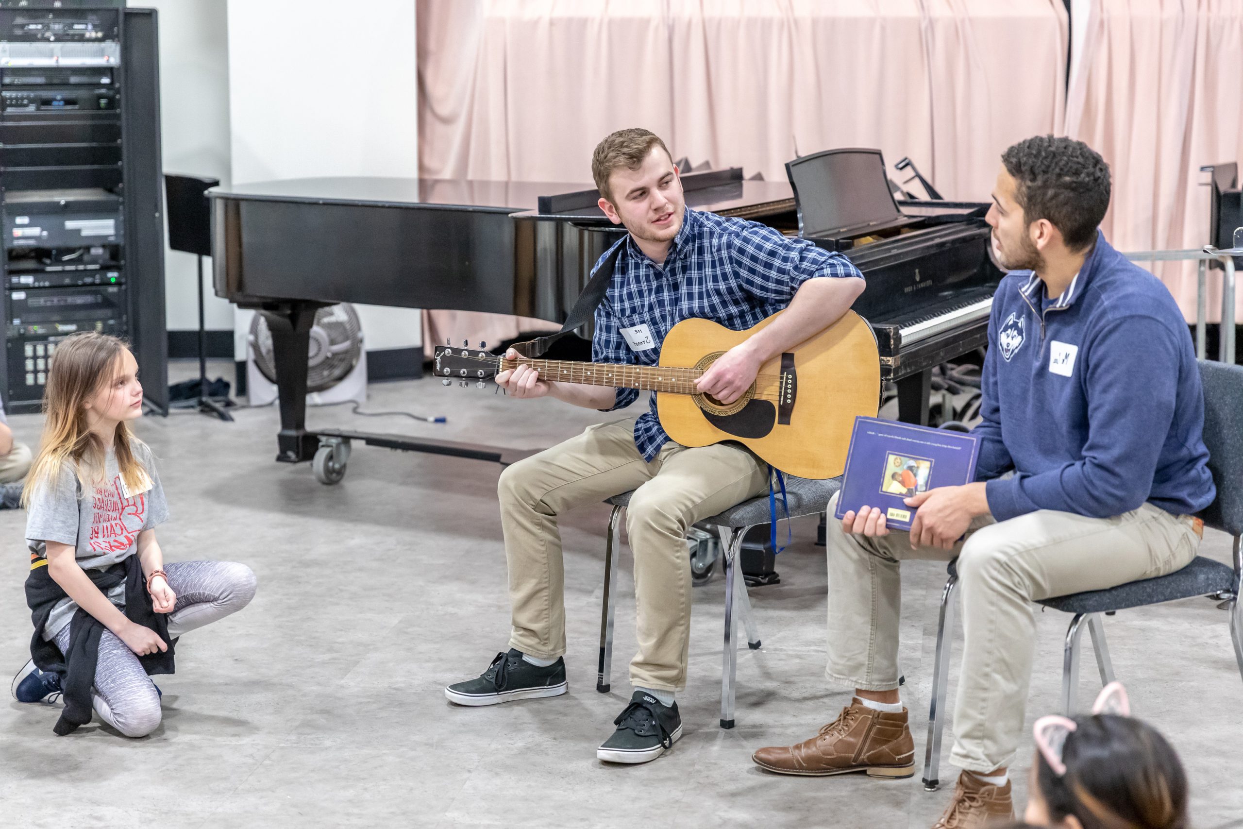 Alumnus Rex Sturdevant '17 (ED), MA '18 plays guitar for a group of elementary students.